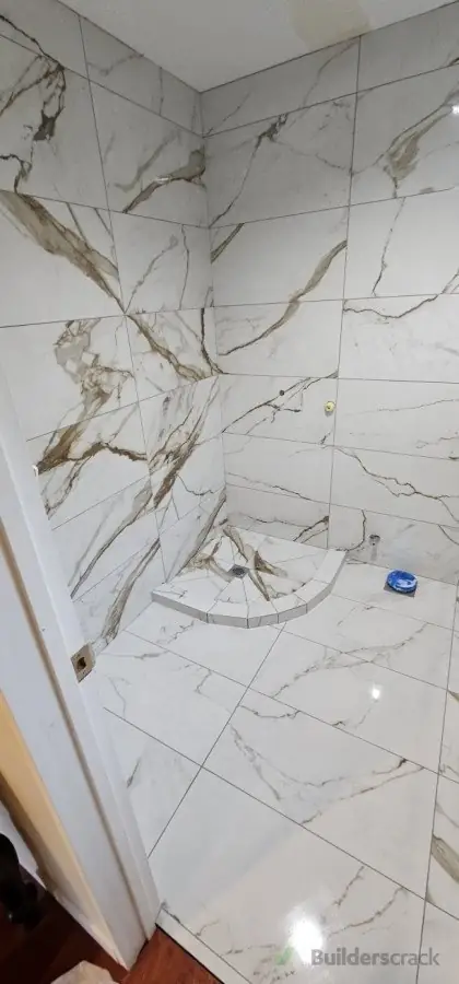 Calacatta marble-look large format porcelain tiles on shower walls, floor and built-in corner seat installed by Dakom Tiling Auckland