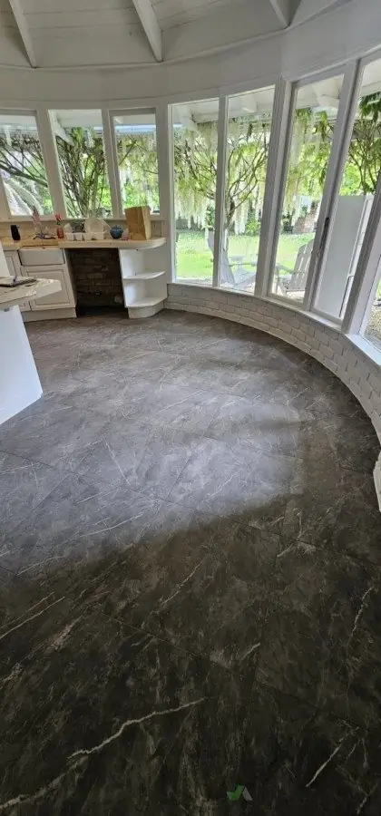 Dark marble-look porcelain floor tiles installed in a curved sunroom conservatory by Dakom Tiling Auckland