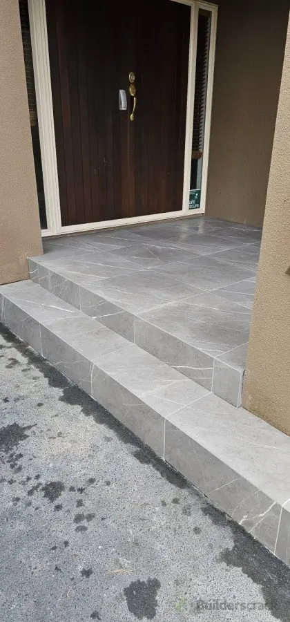 Side angle view of grey porcelain tiled entrance steps and landing installed by Dakom Tiling Auckland