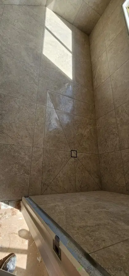 Travertine-look large format wall and floor tiles in a bathroom with linear drain installed by Dakom Tiling Auckland