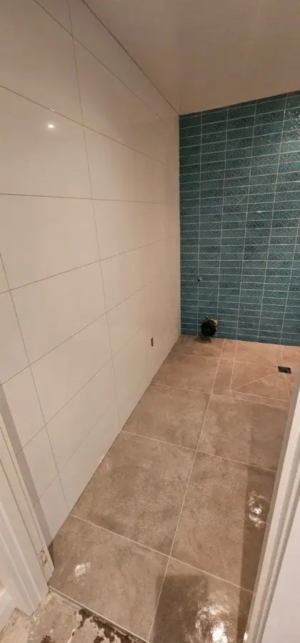 White large format wall tiles with teal green mosaic feature wall and stone-look floor tiles in a bathroom by Dakom Tiling Auckland